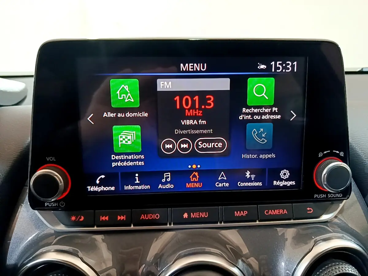 Écran tactile central du tableau de bord du Nissan Juke Hybrid 143 Business+ gris foncé, affichant la radio FM à 101.3 MHz.