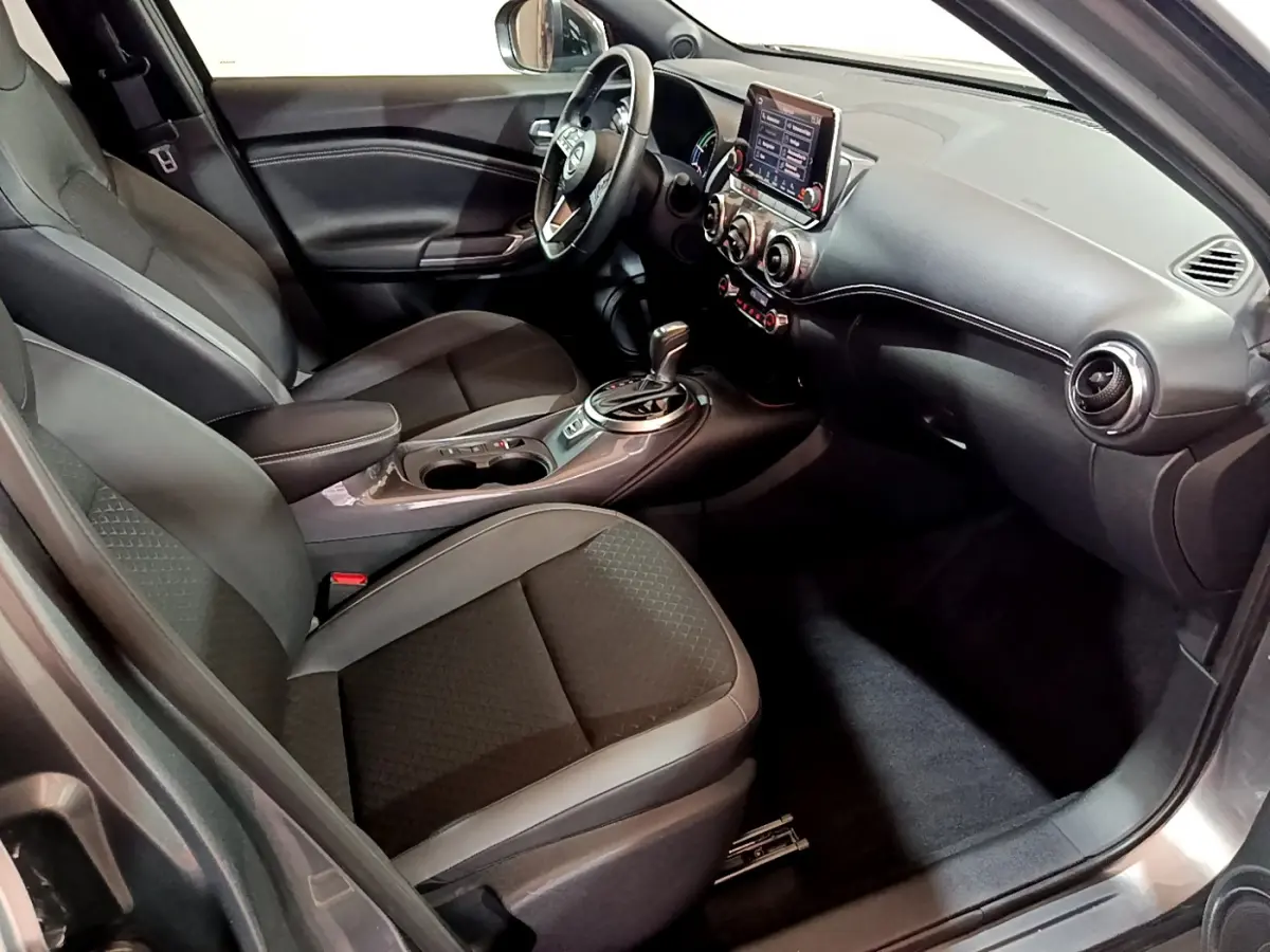 Intérieur avant droit du Nissan Juke Hybrid 143 Business+ 2023 avec sièges noirs et tableau de bord moderne.