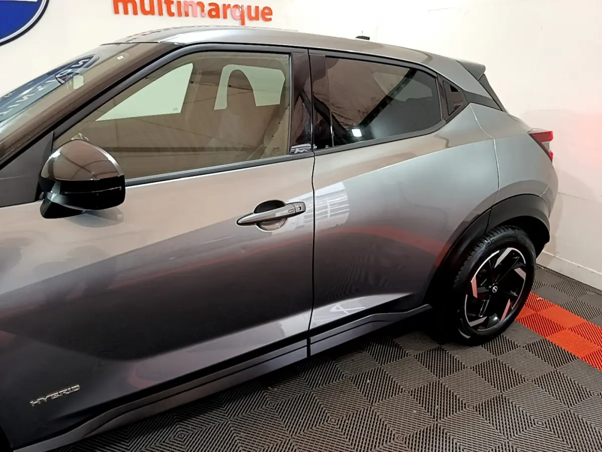 Vue côté gauche du Nissan Juke Hybrid gris foncé 2023, mettant en valeur la porte et la jante noire au design moderne.