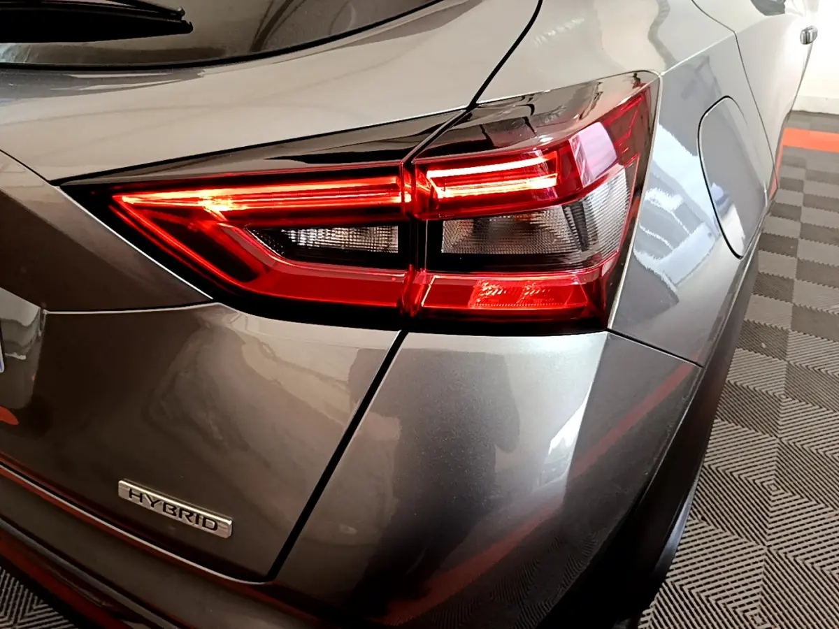 Gros plan sur le feu arrière droit rouge et gris foncé d'un Nissan Juke Hybrid 143 Business+ 2023 avec logo Hybrid visible.