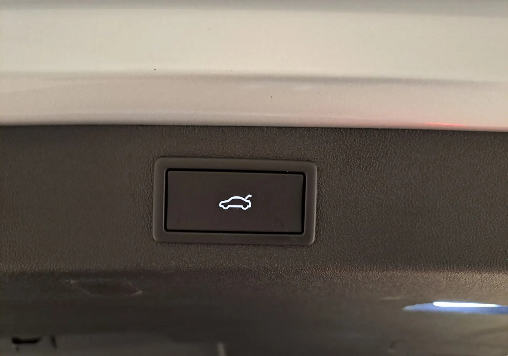 Bouton d'ouverture électrique du hayon sur un Skoda Kodiaq gris argent, vue en gros plan intérieur du coffre.