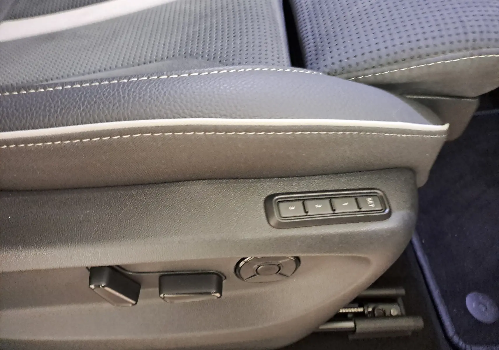 Détail du réglage électrique des sièges avant avec mémoire sur le côté gauche d’un Skoda Kodiaq gris argent.