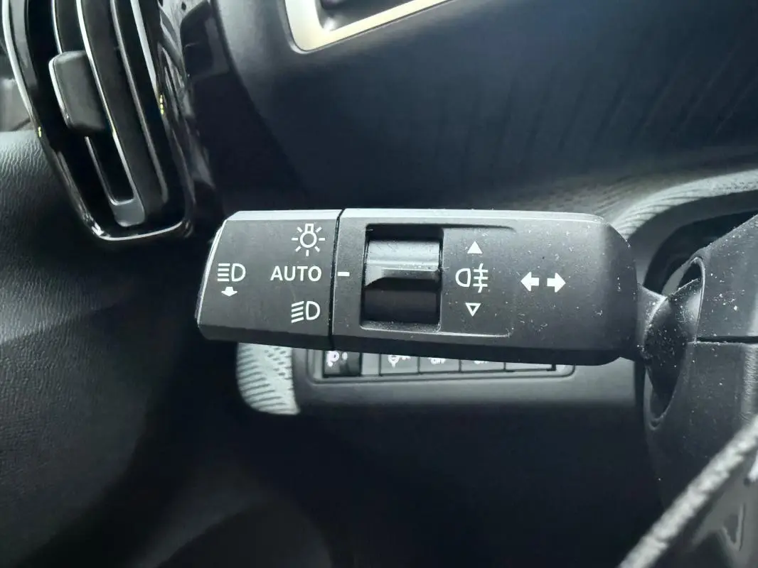 Gros plan sur la commande de feux automatique et clignotants à gauche du volant d'une Citroën C3 gris 2025.
