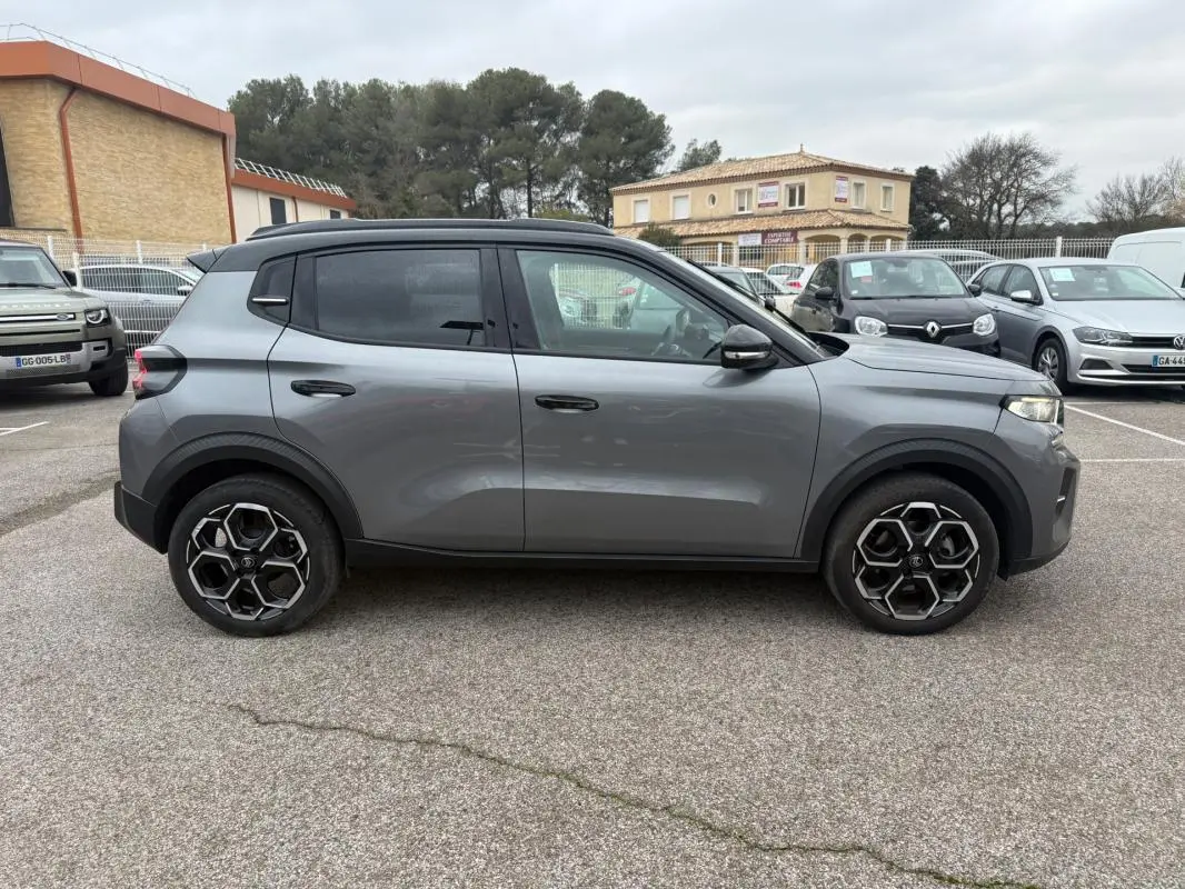 Profil droit d'une Citroën C3 gris 2025 avec jantes alliage noires et toit noir, stationnée en extérieur.