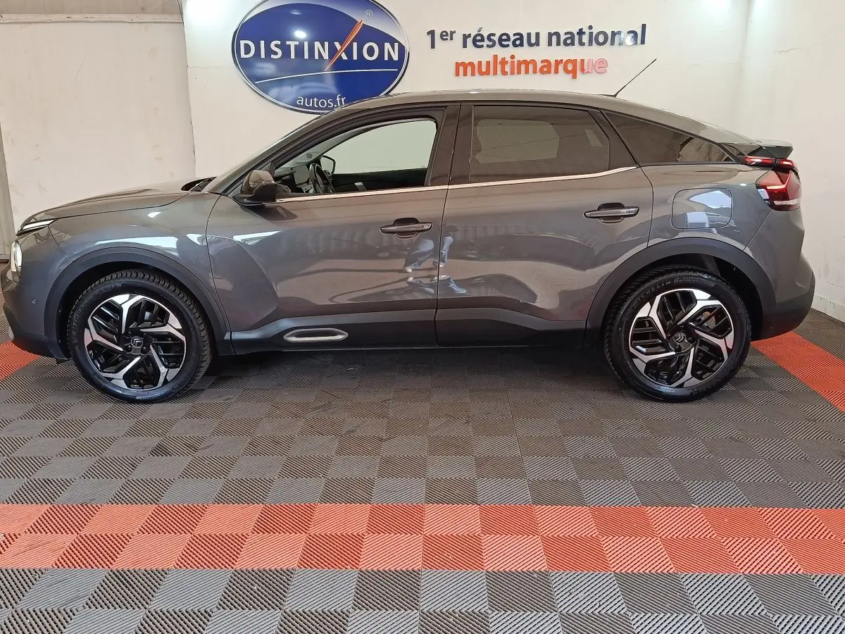 Vue de profil côté gauche d'une Citroën C4 gris foncé 2022 avec jantes noires et toit noir brillant.