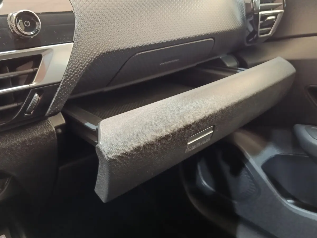 Gros plan sur la boîte à gants ouverte de l’habitacle noir d’une Citroën C4 2022, finition Shine.