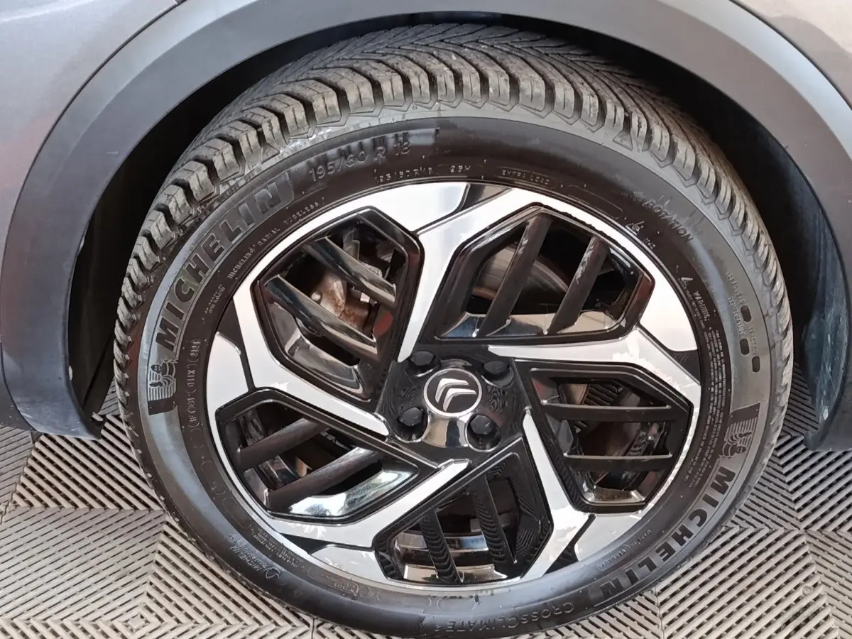 Gros plan sur la roue avant droite avec jante alliage bicolore noire et argentée du Citroën C4 gris foncé.