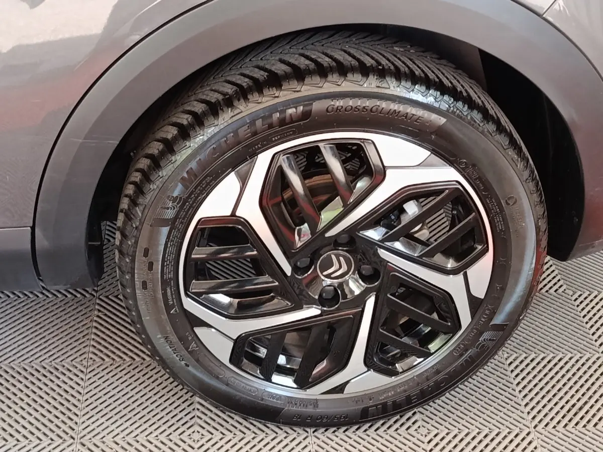 Gros plan sur la roue avant droite d'une Citroën C4 gris foncé, avec jante alliage bicolore et pneu Michelin.