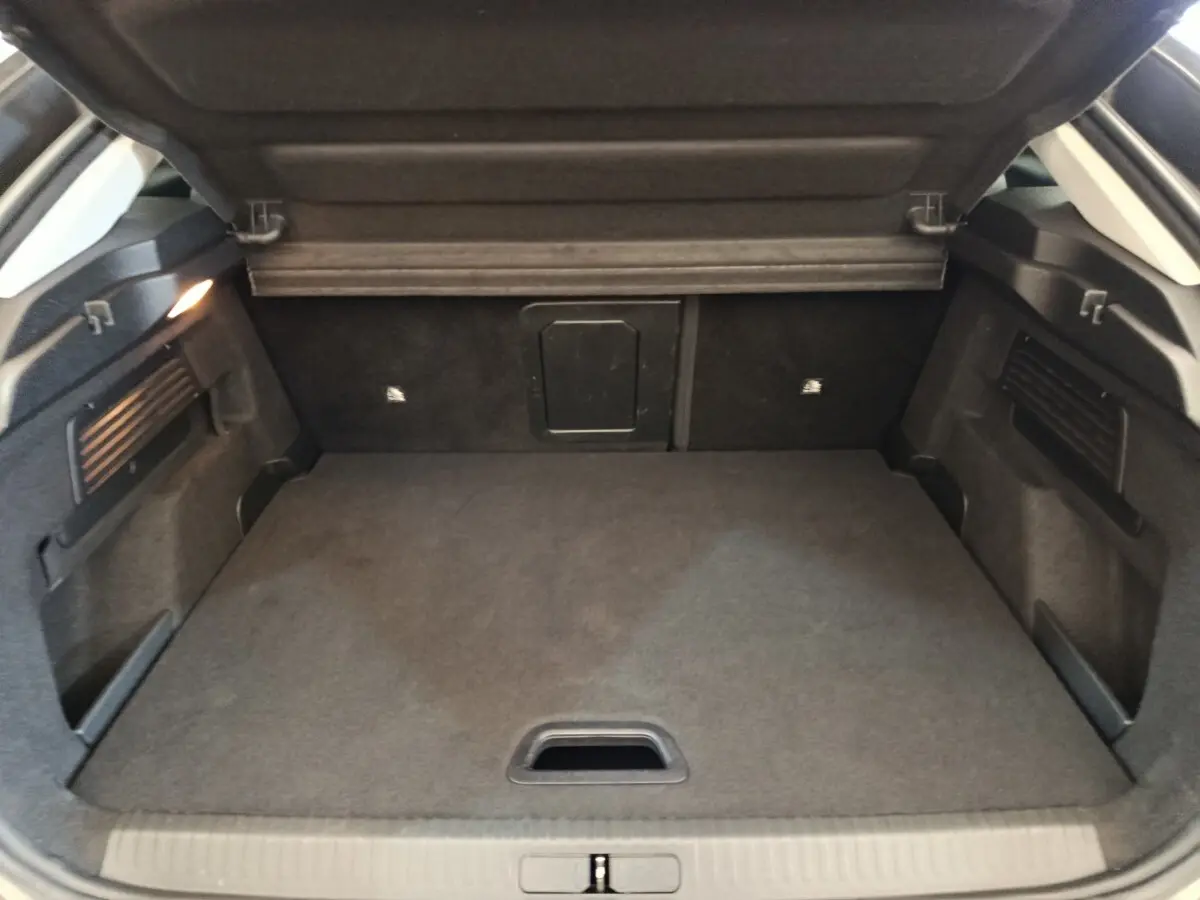 Coffre ouvert vu de face d’une Citroën C4 2022 gris foncé, espace de chargement propre et bien éclairé.