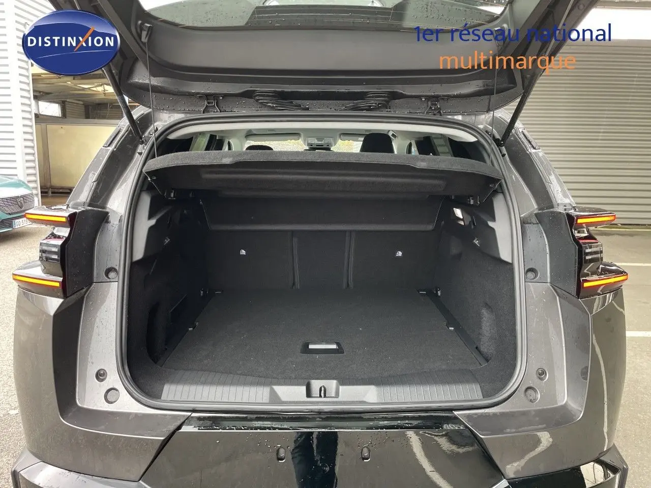Vue arrière du coffre ouvert d'un Citroën C5 Aircross Hybrid gris platinium métal, avec feux arrière allumés.