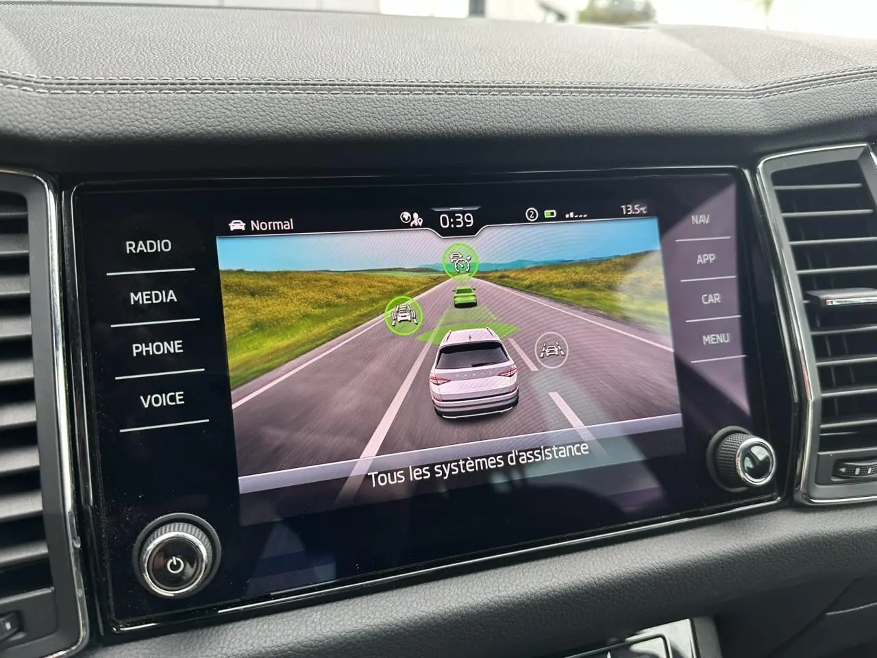 Écran central du Skoda Kodiaq 2024 montrant l'interface d'assistance à la conduite avec vue routière virtuelle.