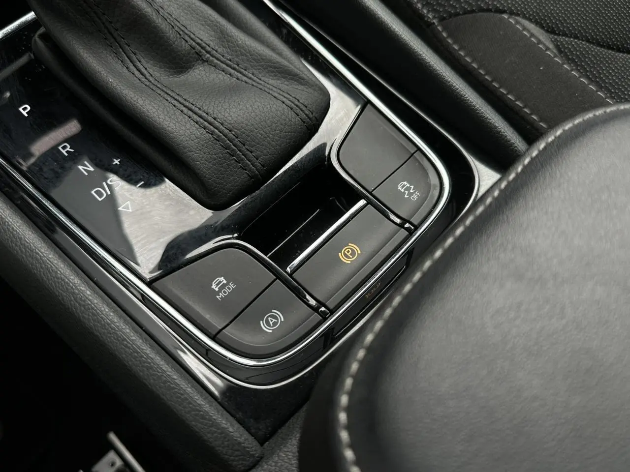 Gros plan sur la console centrale noire du Skoda Kodiaq 2024, avec levier de vitesses automatique et boutons de contrôle.