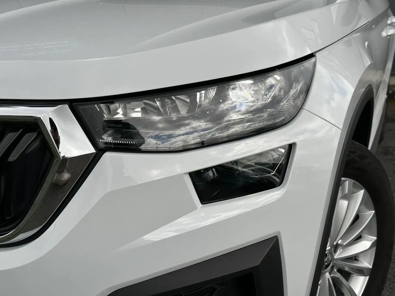 Gros plan sur l'avant droit du Skoda Kodiaq blanc Glacier, mettant en valeur le phare LED et la jante alliage 18 pouces.