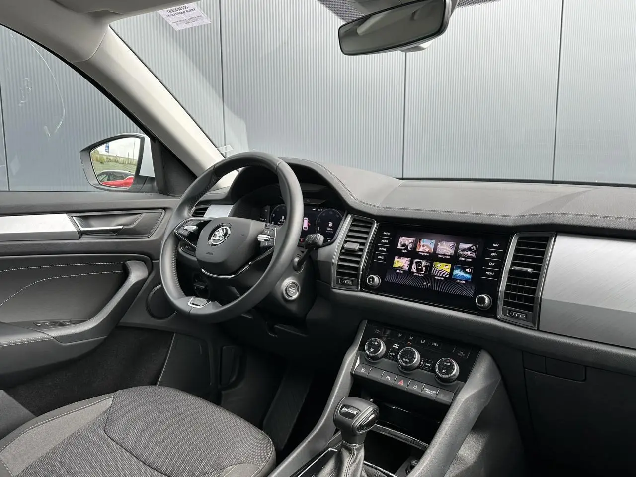 Vue intérieure côté conducteur du Skoda Kodiaq blanc Glacier 2024, avec tableau de bord digital et écran tactile central.