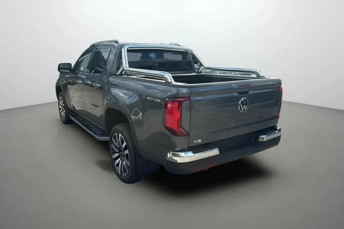Vue 3/4 arrière droite du Volkswagen Amarok simple cabine 2025 gris foncé avec barres de protection chromées et logo V6.