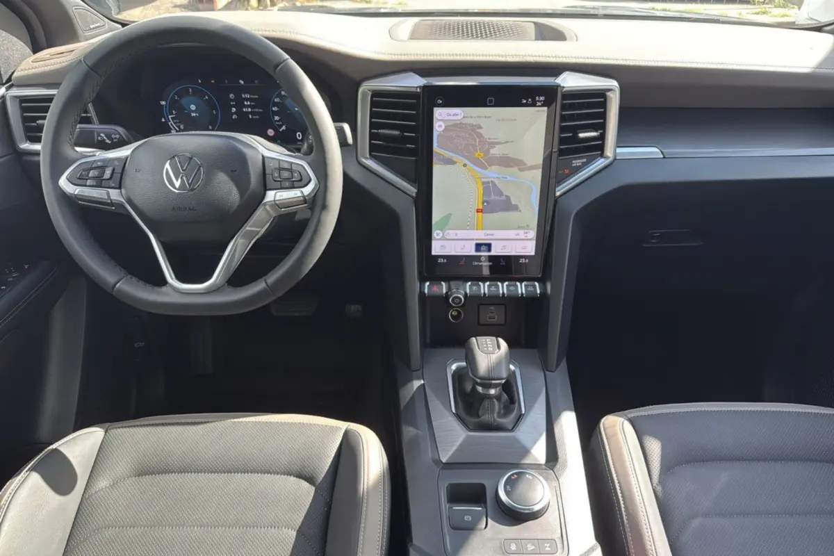 Vue intérieure avant du Volkswagen Amarok Simple Cabine 2025, avec tableau de bord numérique et écran tactile central affichant la navigation.