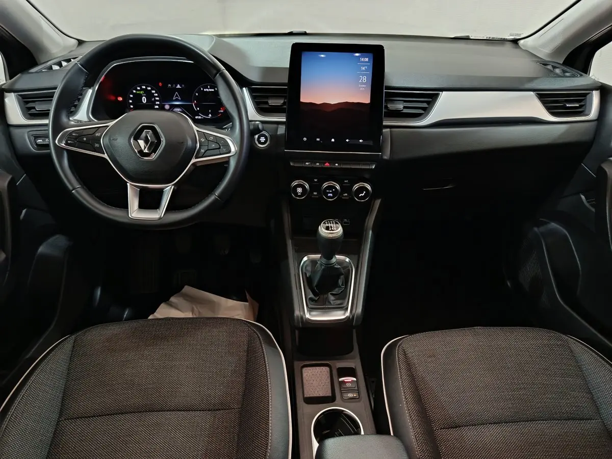 Vue frontale de l'intérieur du Renault Captur techno TCe 90 2024, avec tableau de bord numérique et écran tactile vertical.