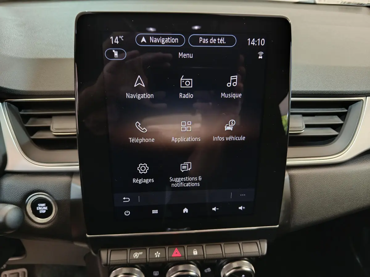Écran tactile central allumé du tableau de bord du Renault Captur gris foncé, avec bouton démarrage visible à gauche.