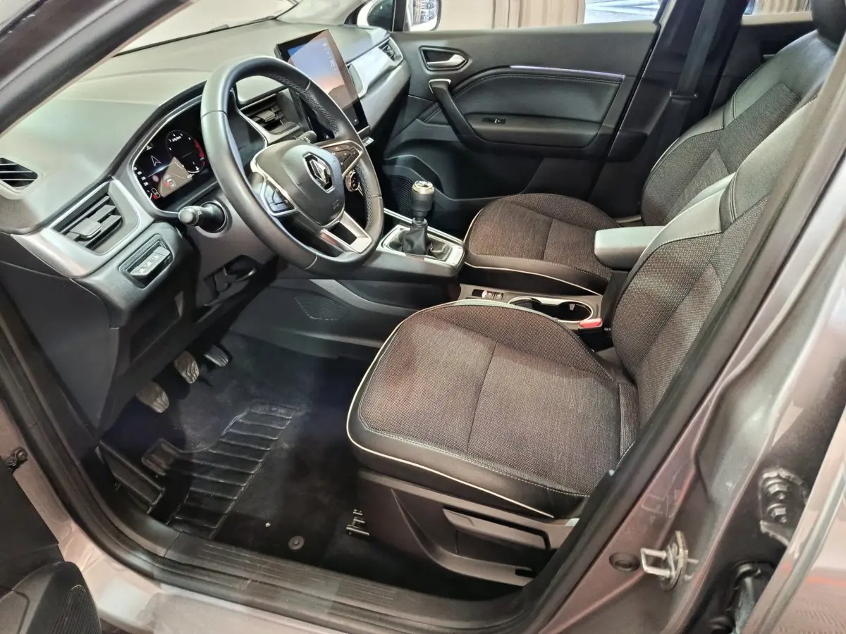 Intérieur avant droit du Renault Captur gris foncé 2024 avec tableau de bord numérique et boîte manuelle.