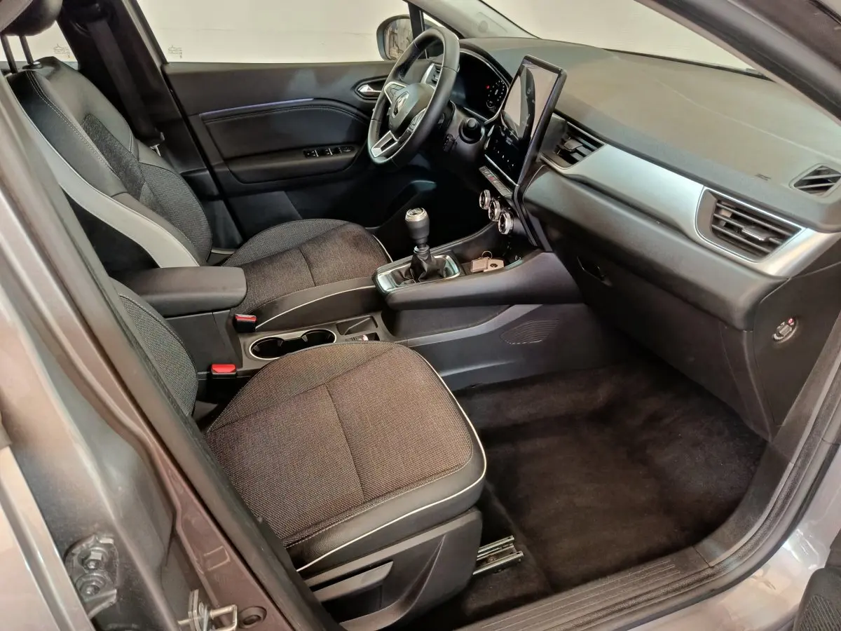 Intérieur côté conducteur du Renault Captur gris foncé 2024, avec tableau de bord moderne et boîte manuelle.