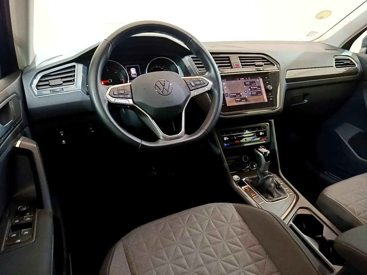 Intérieur du Volkswagen Tiguan 2021, vue du poste de conduite avec volant cuir multifonctions et écran tactile central.