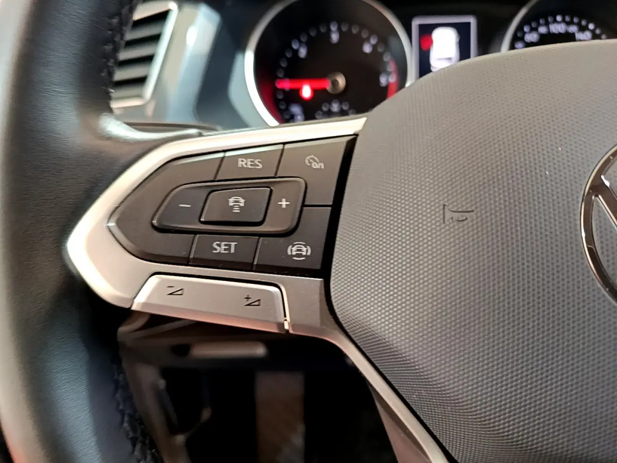 Gros plan sur le volant cuir noir du Volkswagen Tiguan 2.0 TDI 150 DSG7 avec commandes de régulateur de vitesse.