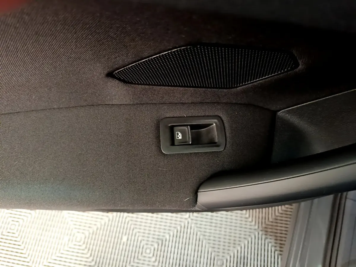 Détail de la commande de lève-vitre sur la porte intérieure noire du Volkswagen Tiguan gris clair 2021.