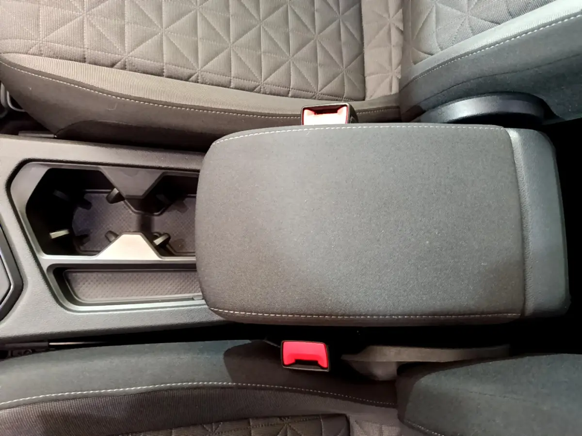 Vue rapprochée de l'accoudoir central gris et porte-gobelets entre les sièges avant du Volkswagen Tiguan 2021.