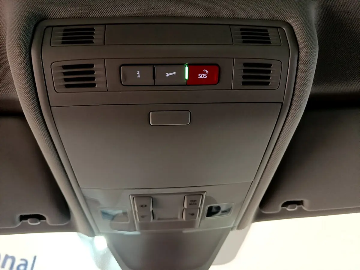 Vue en contre-plongée du panneau de commande intérieur gris du toit d'un Volkswagen Tiguan 2.0 TDI 150 DSG7 Life Business avec bouton SOS rouge allumé.