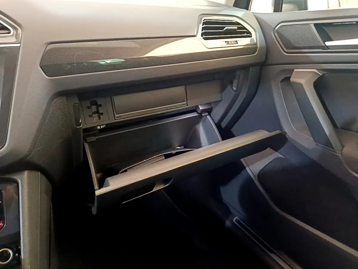 Intérieur du Volkswagen Tiguan 2.0 TDI 2021 montrant la boîte à gants ouverte côté passager, finition gris foncé.