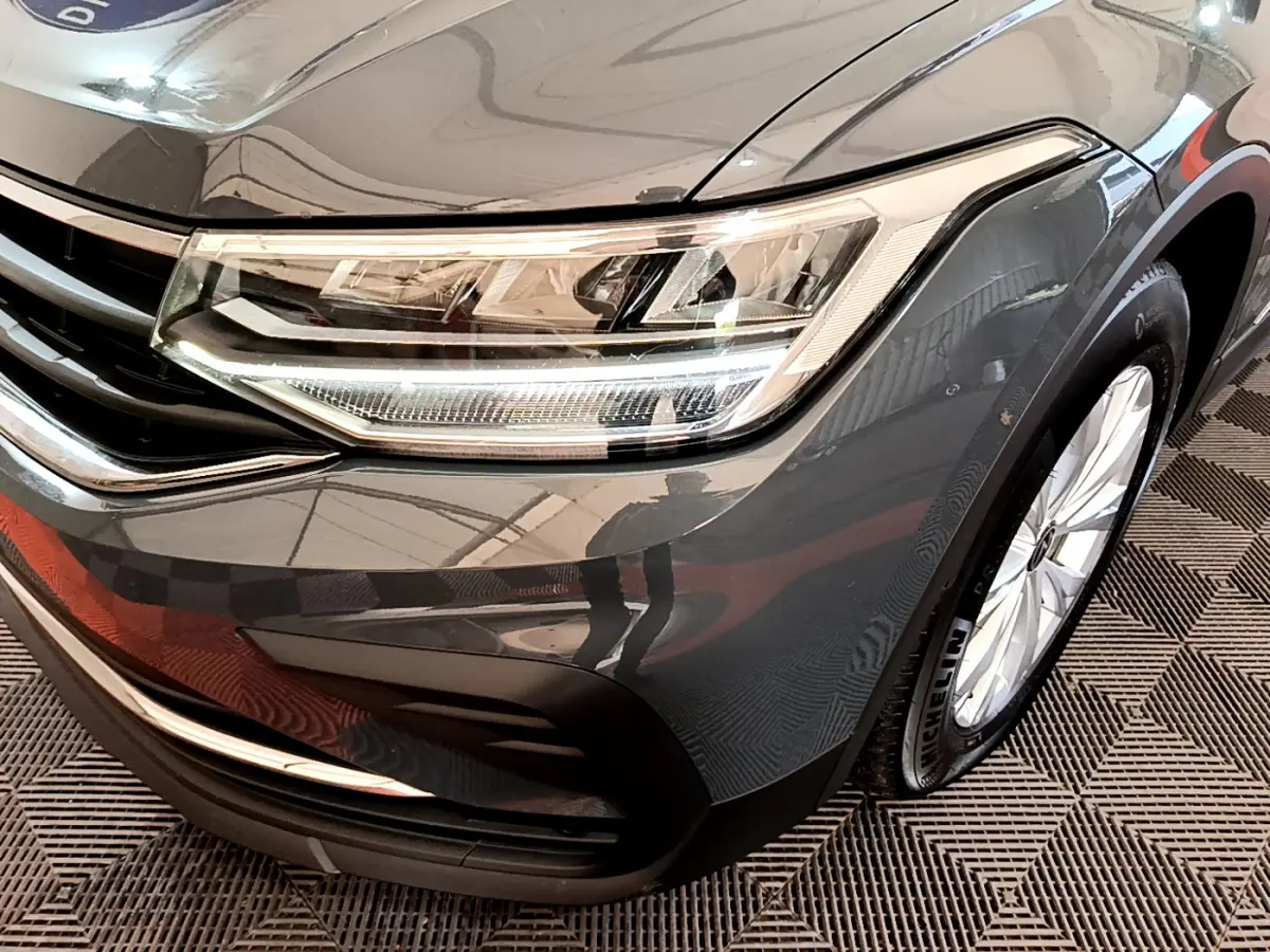 Gros plan sur l'avant droit gris clair du Volkswagen Tiguan 2.0 TDI 150 DSG7 avec phare LED et jante alliage.