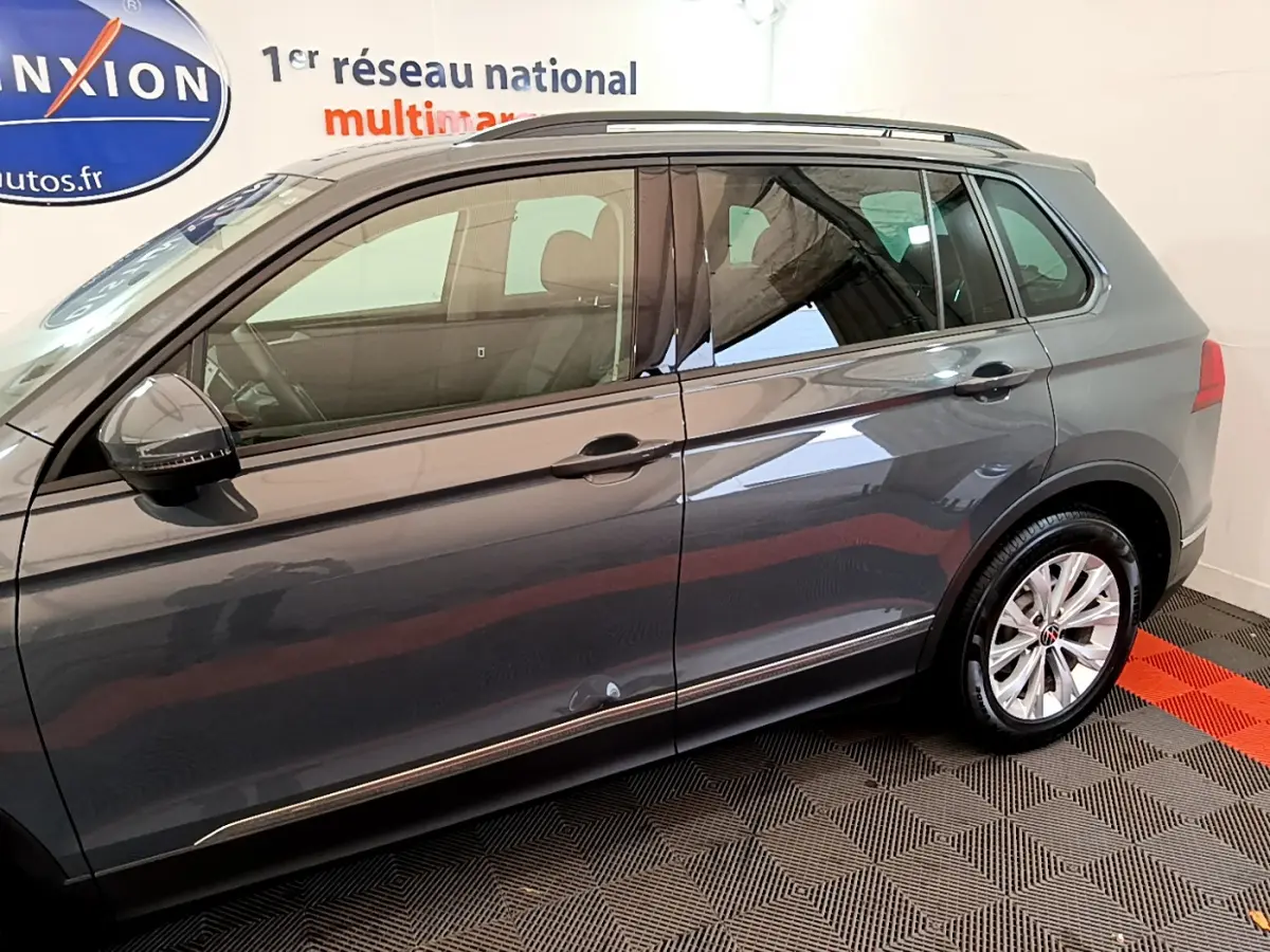 Profil côté gauche d'un Volkswagen Tiguan gris clair 2021 avec jantes alliage et rétroviseurs noirs brillants.