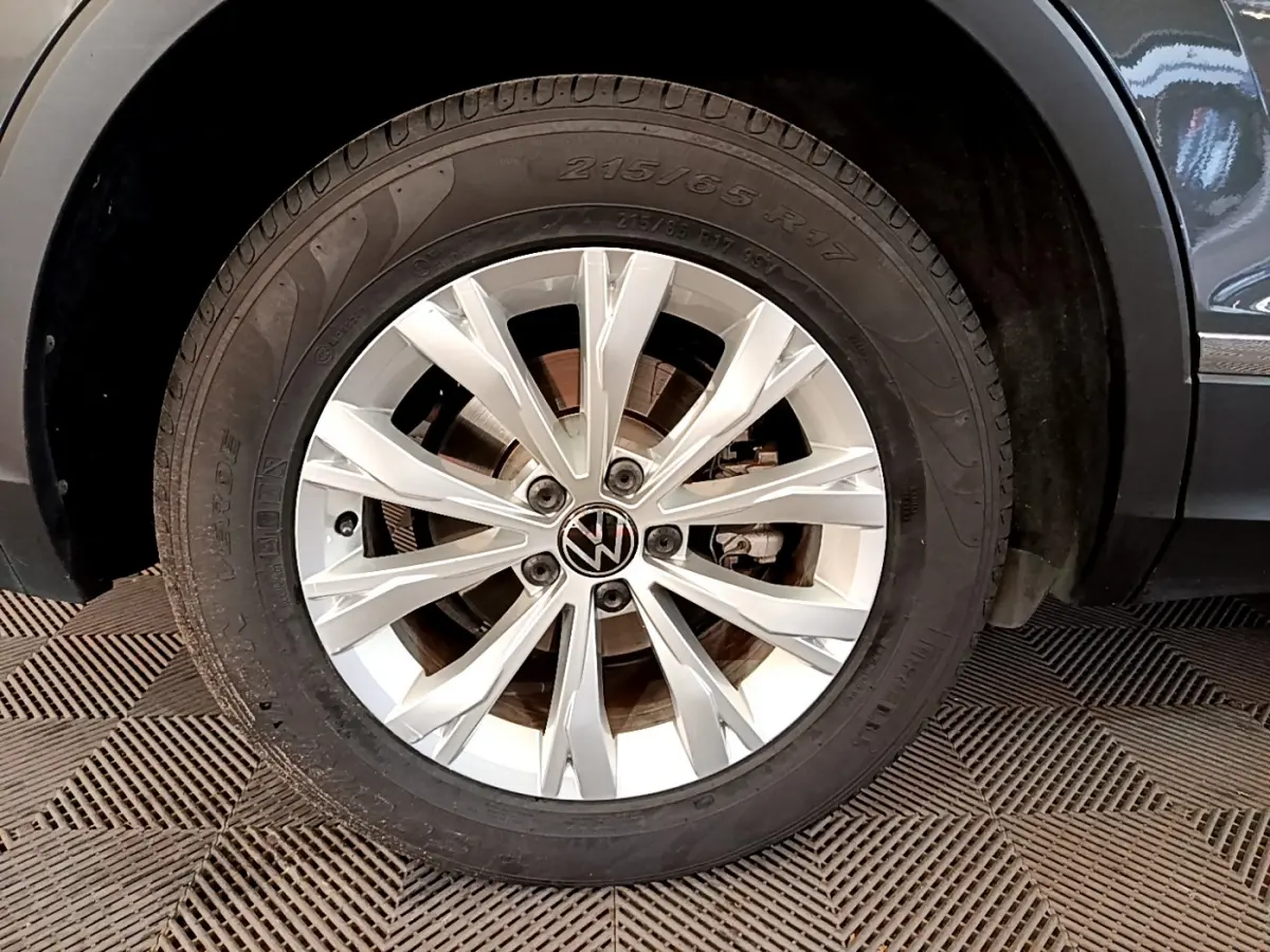 Gros plan sur la roue avant droite du Volkswagen Tiguan gris clair, mettant en valeur la jante en alliage moderne.