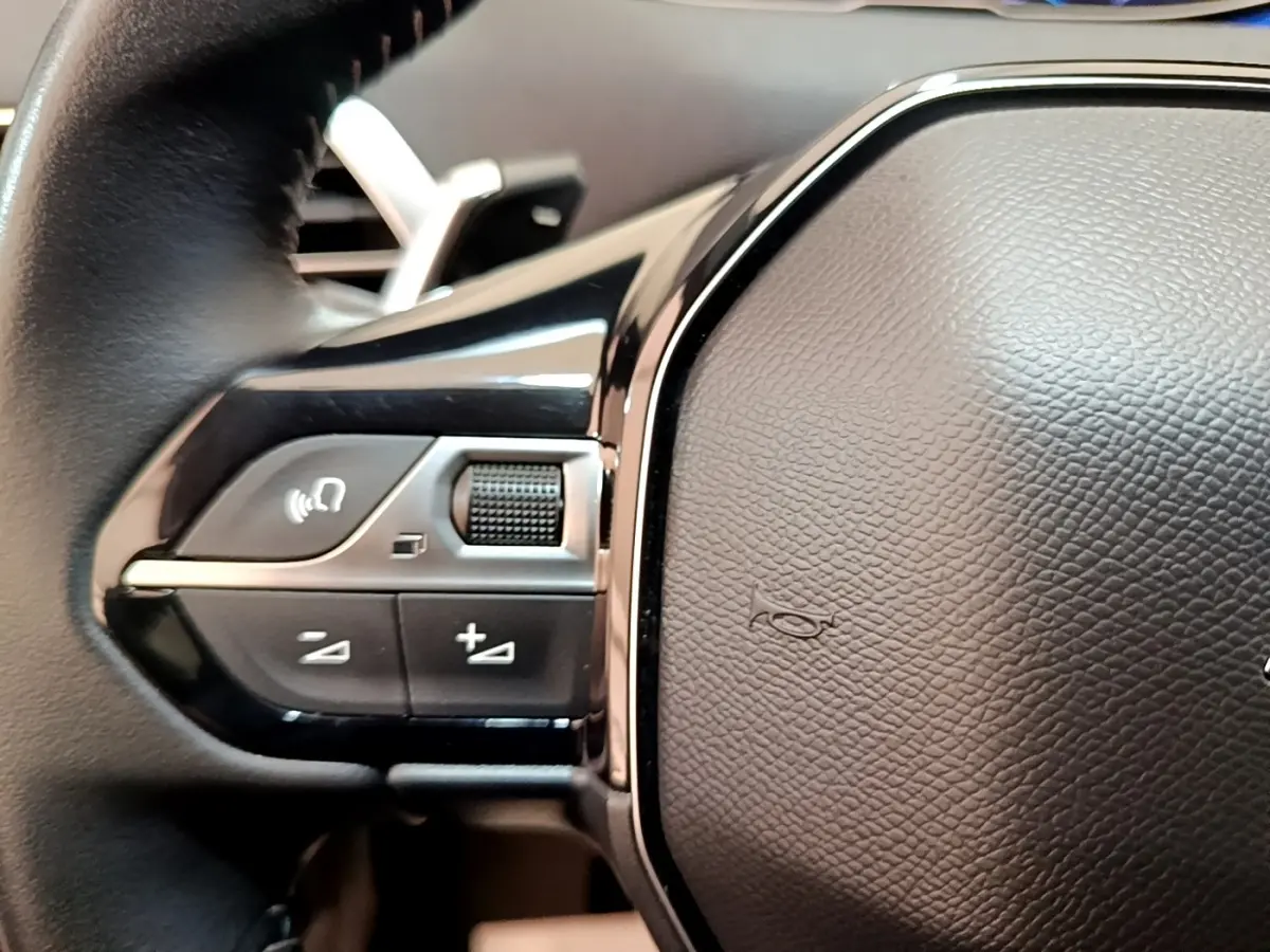Gros plan sur les commandes gauche du volant cuir du Peugeot 3008 gris foncé, version BlueHDi 130 Allure 2022.