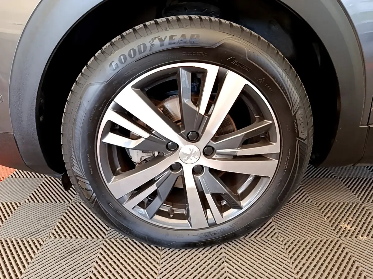 Gros plan sur la roue avant gauche du Peugeot 3008 gris foncé, avec jante alliage et pneu Goodyear visible.