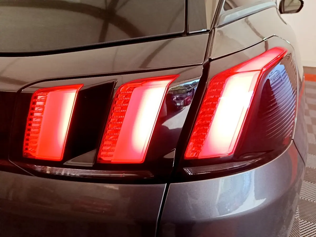 Gros plan sur le feu arrière droit rouge du Peugeot 3008 gris foncé, mettant en valeur son design en trois griffes.