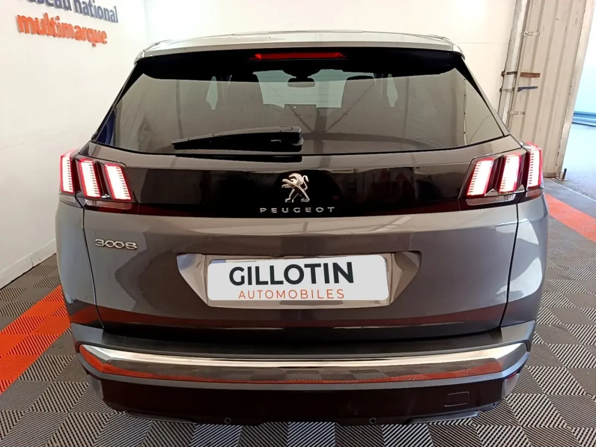 Vue arrière d’un Peugeot 3008 gris foncé avec feux arrière allumés et logo lion visible.