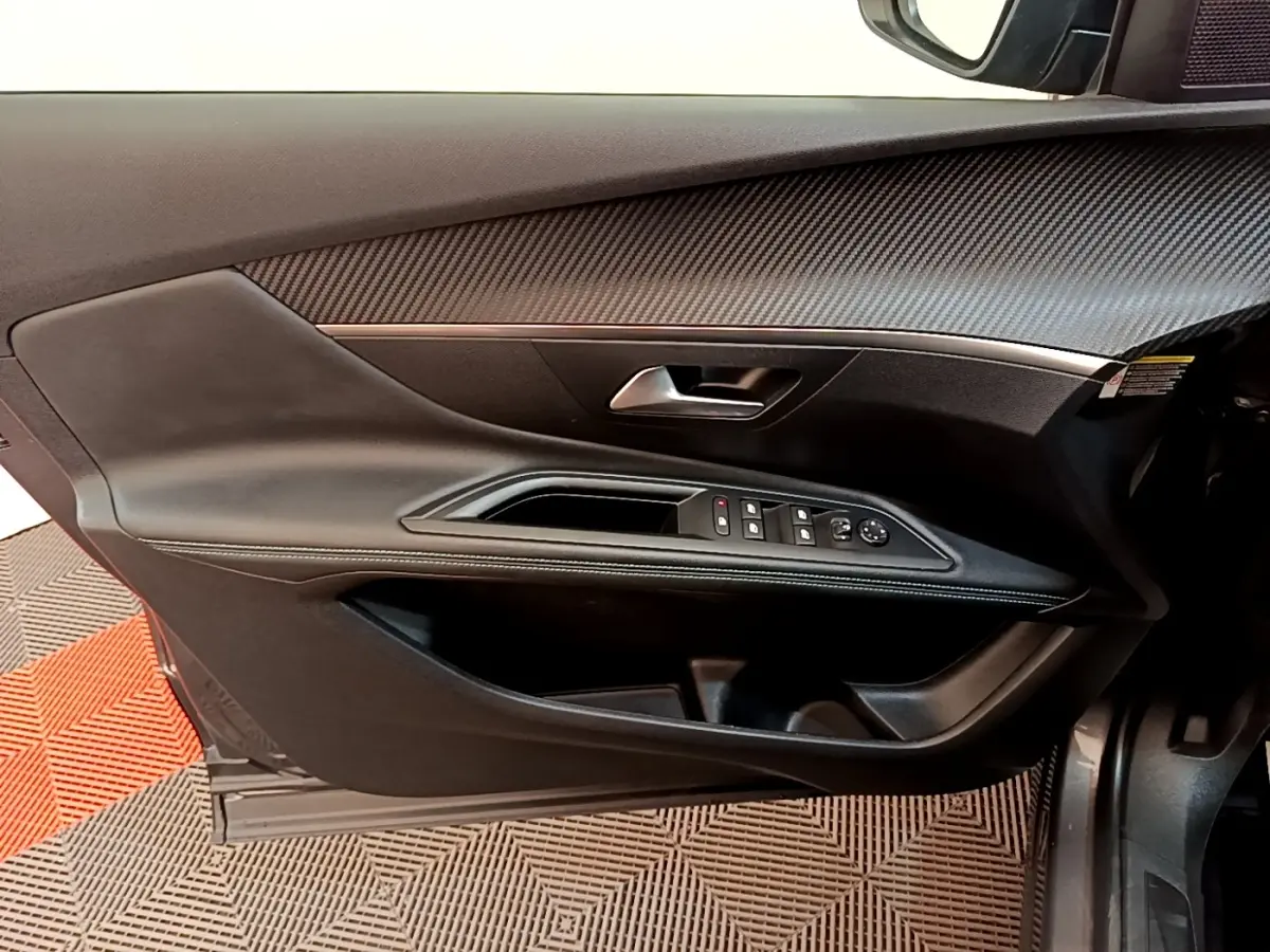 Vue intérieure côté gauche de la porte avant d'un Peugeot 3008 gris foncé, avec commandes de vitres et rétroviseurs.