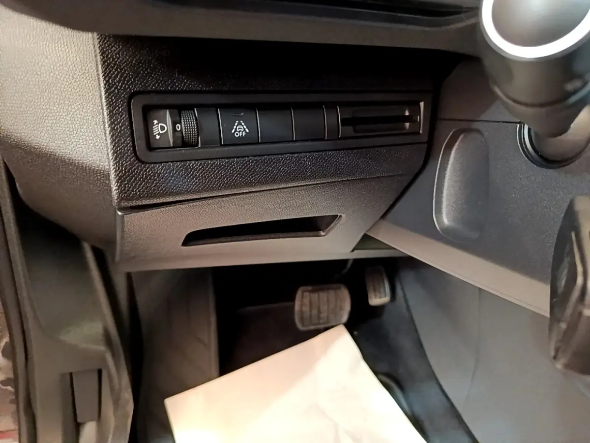 Vue intérieure côté conducteur du Peugeot 3008 gris foncé, avec commandes d’éclairage et pédales visibles.