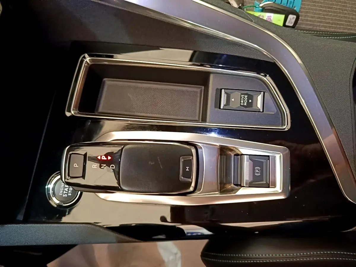 Vue rapprochée de la console centrale noire brillante du Peugeot 3008 2022 avec levier de vitesses automatique et bouton start/stop.