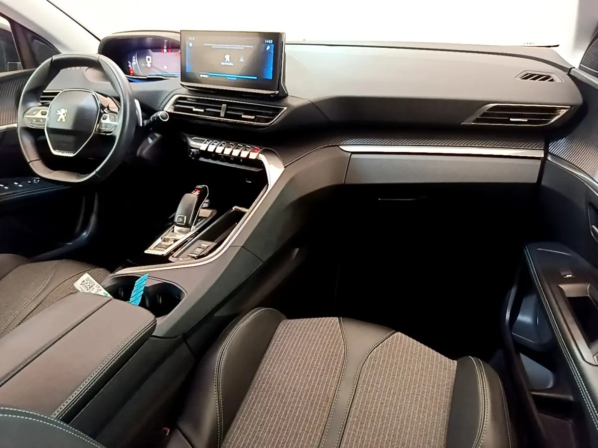 Vue intérieure côté passager du tableau de bord et console centrale du Peugeot 3008 gris foncé avec écran tactile et volant cuir.