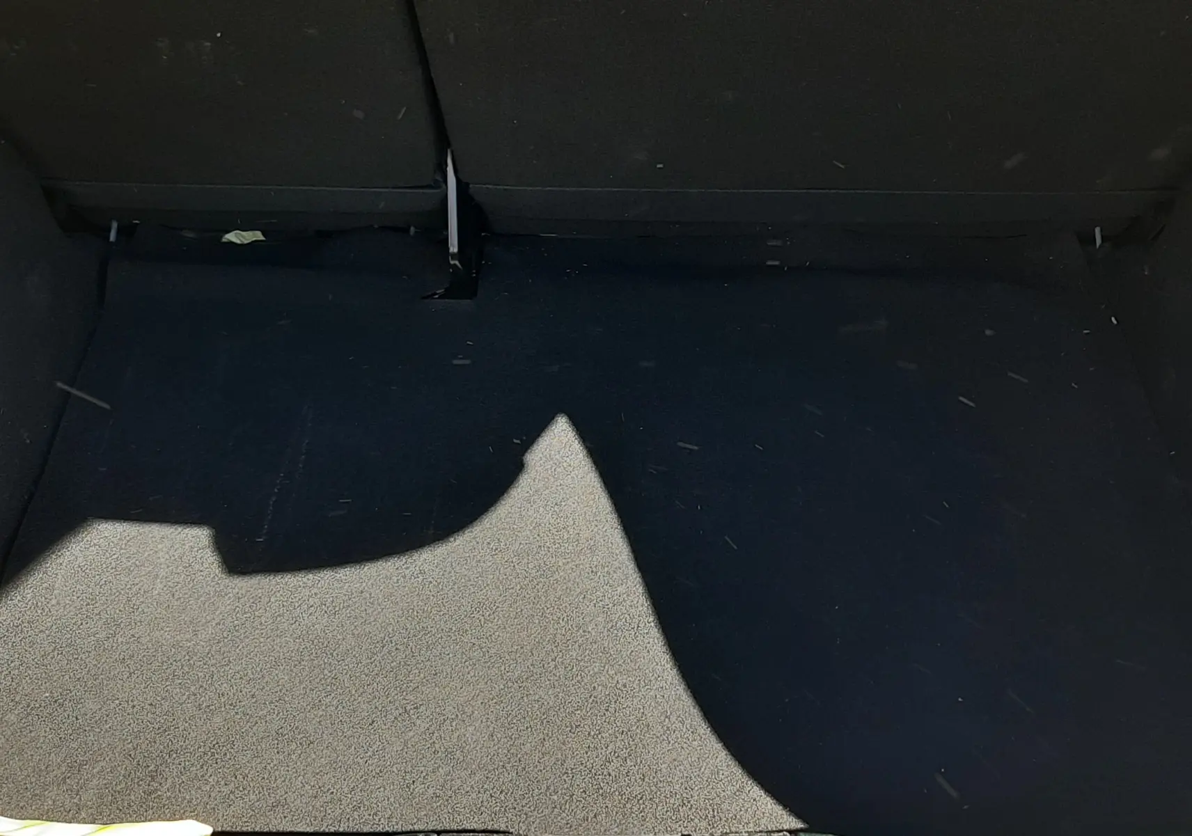 Coffre ouvert vu de face d'une Dacia Sandero Stepway vert cèdre, montrant le tapis de coffre noir et la bordure arrière.