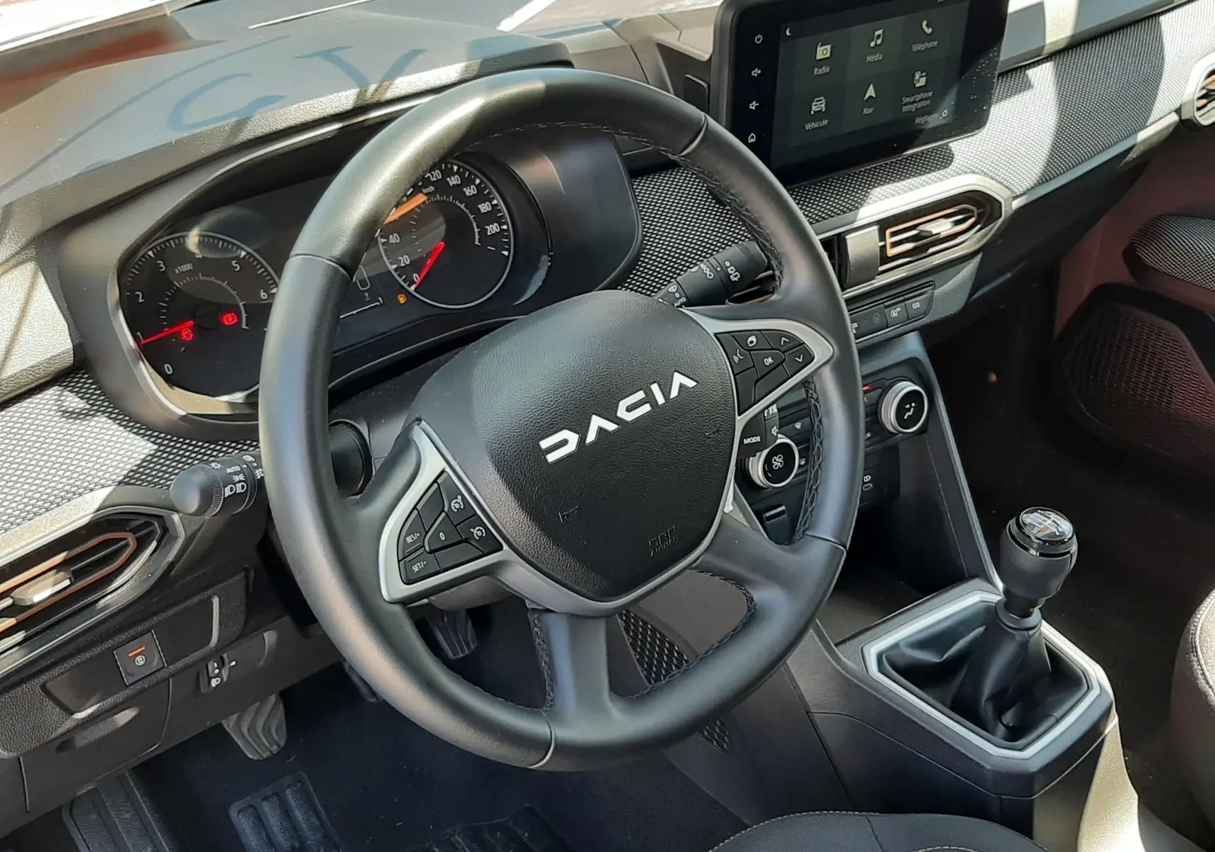 Vue intérieure du poste de conduite de la Dacia Sandero Stepway 2025, volant multifonction, écran tactile et boîte manuelle.