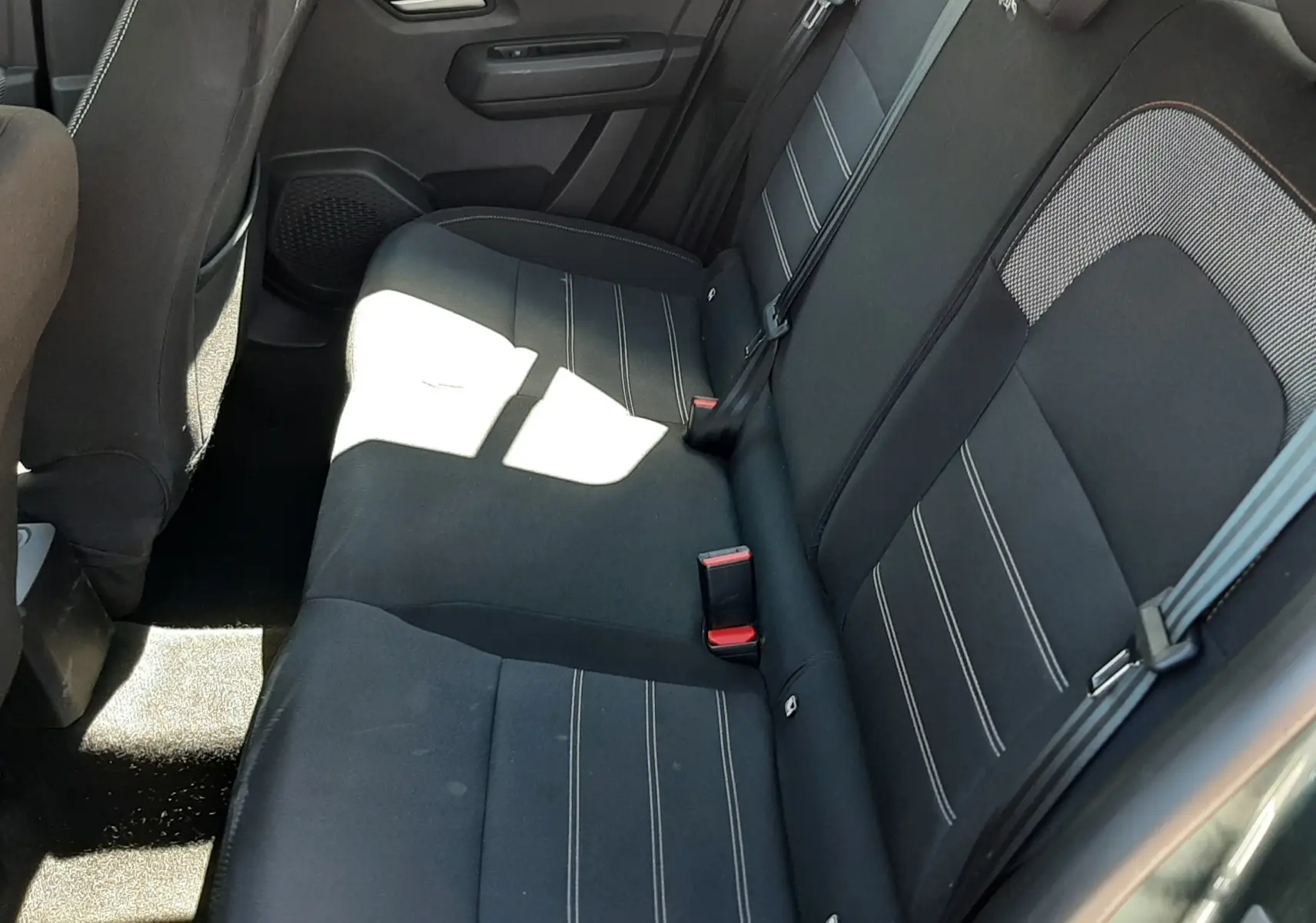Vue intérieure côté arrière droit de la banquette tissu gris foncé avec surpiqûres blanches de la Dacia Sandero Stepway 2025.
