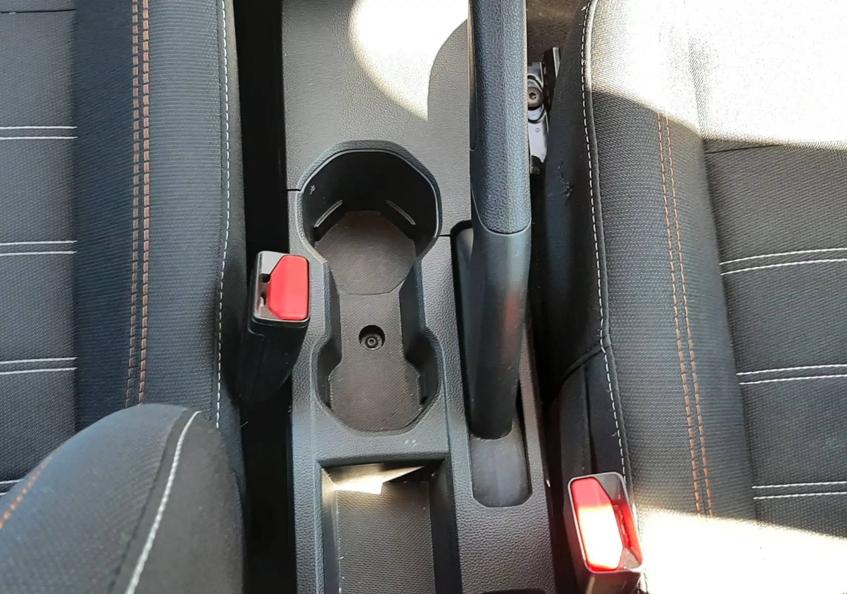 Vue plongeante sur la console centrale intérieure du Dacia Sandero Stepway 2025, sièges gris tissu avec surpiqûres orange.