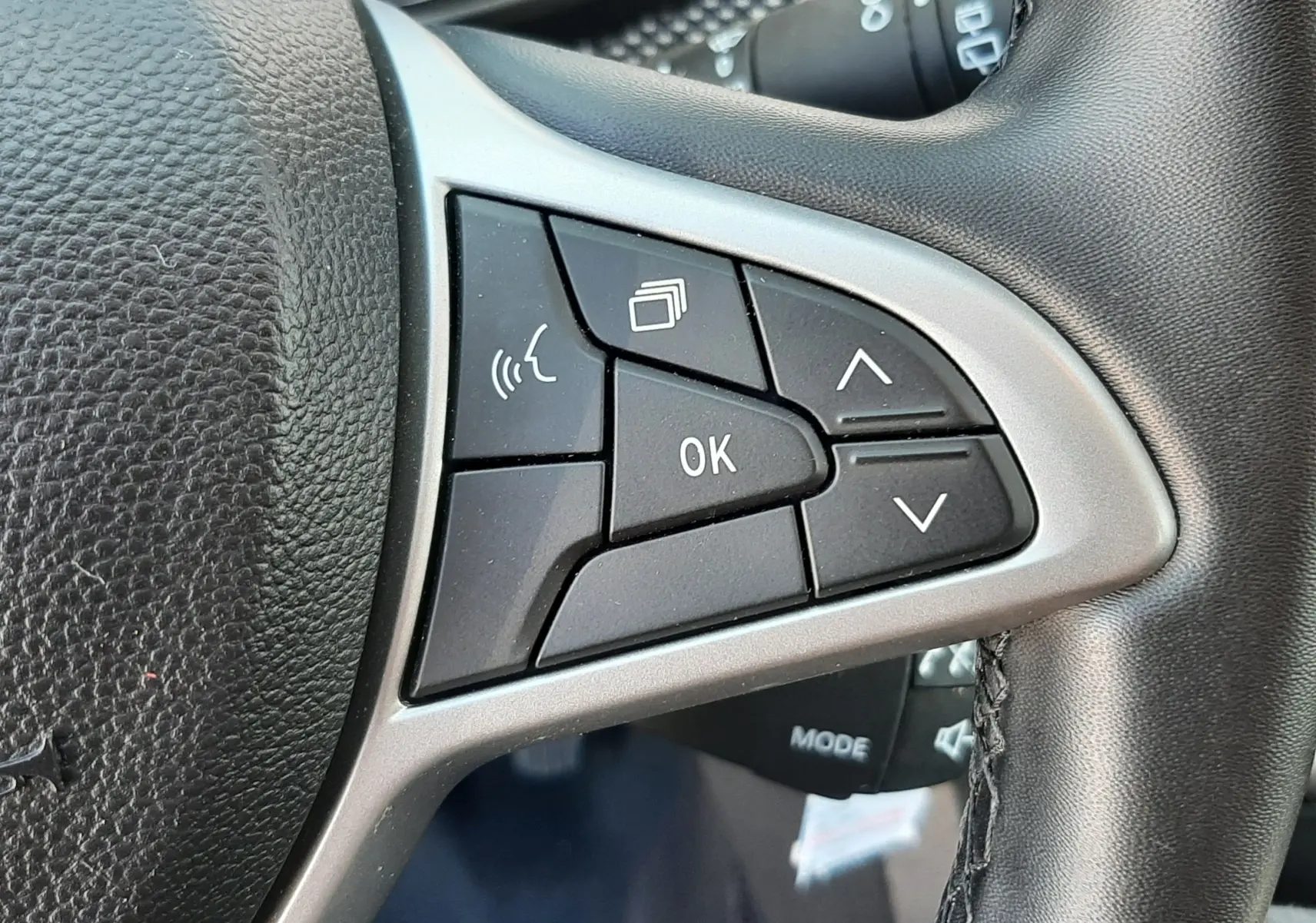 Gros plan sur les commandes multifonctions à droite du volant en cuir noir de la Dacia Sandero Stepway 2025.