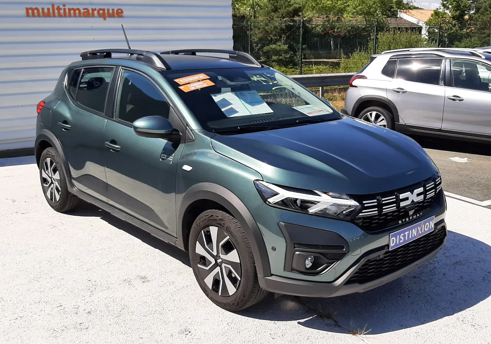Vue 3/4 avant droite d'une Dacia Sandero Stepway 2025 vert cèdre avec barres de toit et jantes alliage.