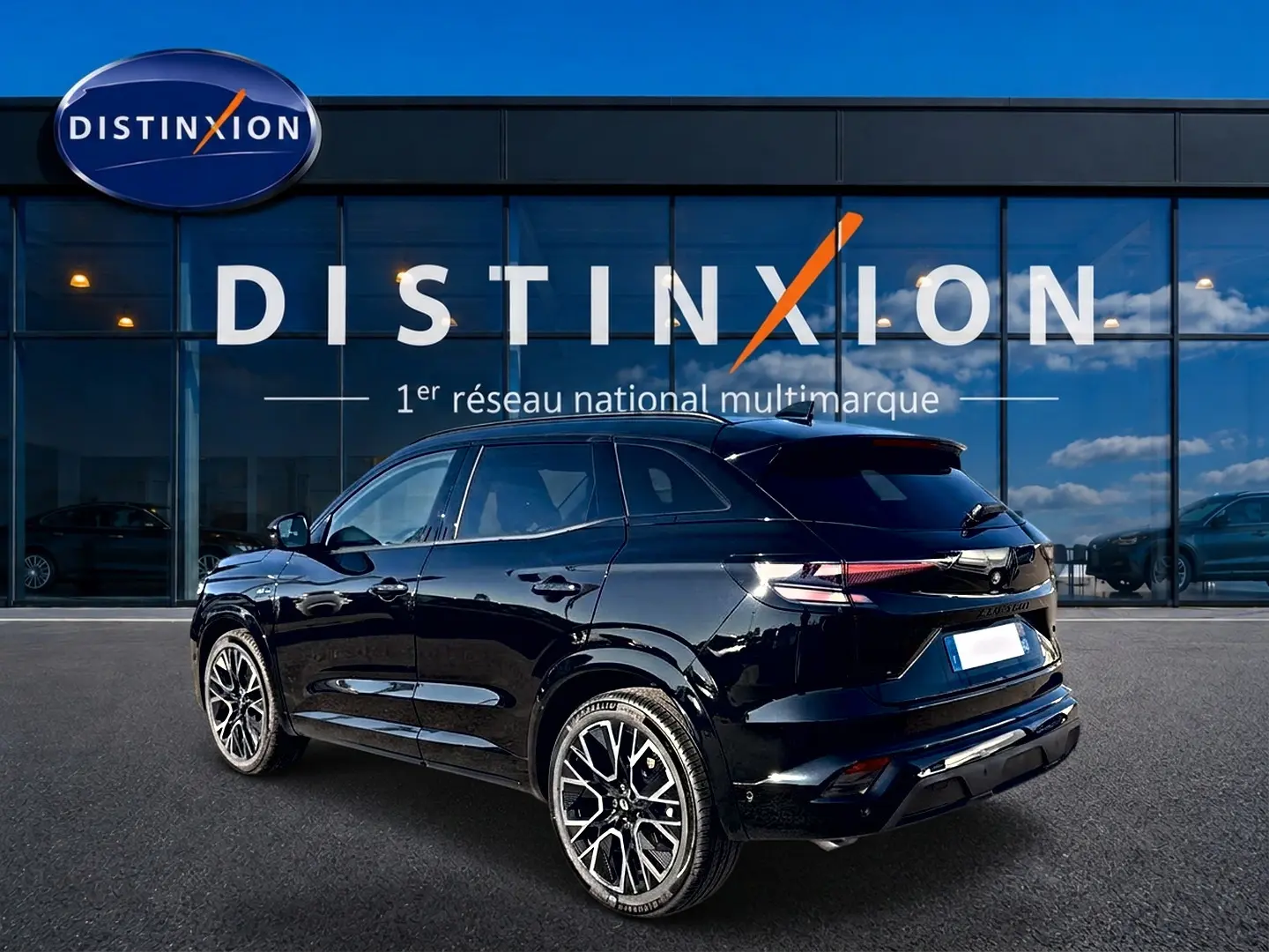 Vue 3/4 arrière d'un Renault Austral noir brillant avec jantes alliage et toit surélevé devant un showroom Distinxion.