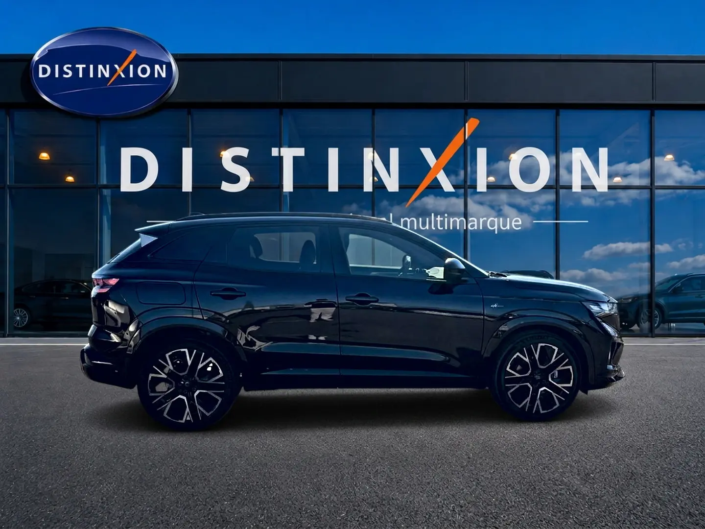 Profil droit du Renault Austral noir 2026 esprit Alpine avec jantes alu distinctives, devant une vitrine multimarque.