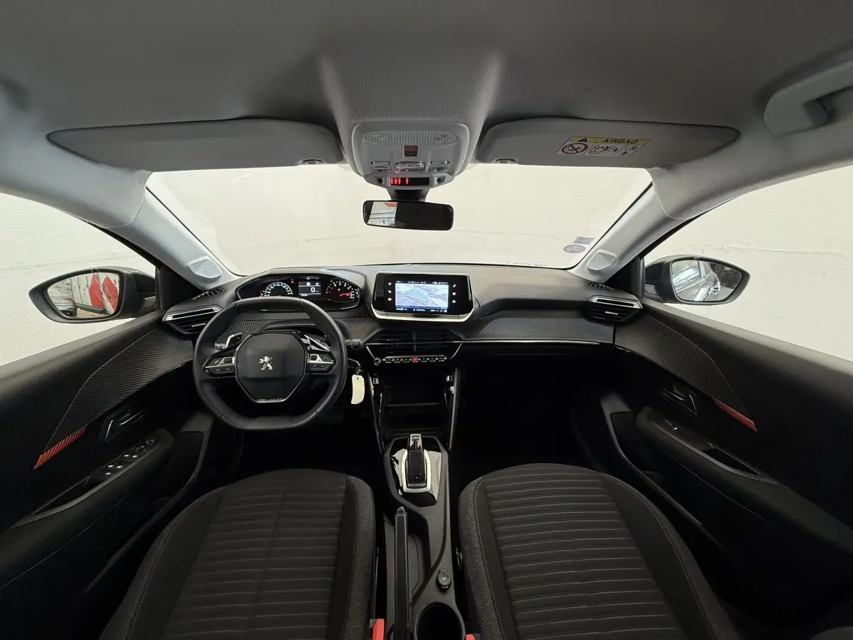 Intérieur noir de la Peugeot 208 2021, vue frontale du tableau de bord avec écran tactile et volant multifonctions.